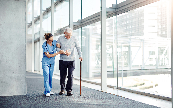 Nurse walks with a patient using a cane