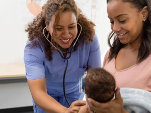 Nurse practitioner talks to a patient and her infant during an appointment