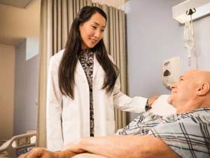 Physician stands over a patient in a hospital room