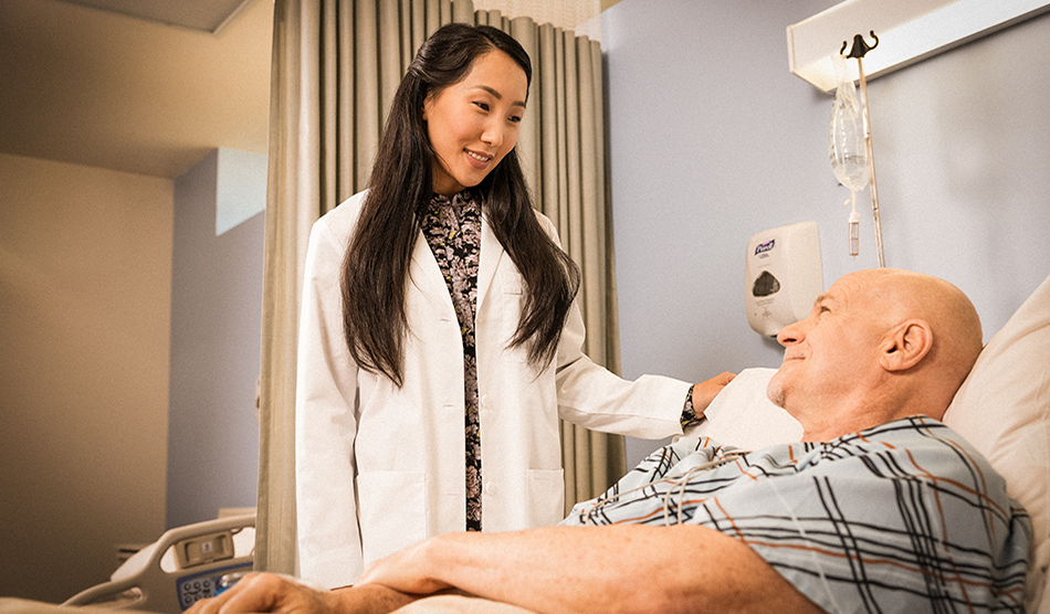 Physician stands over a patient in a hospital room