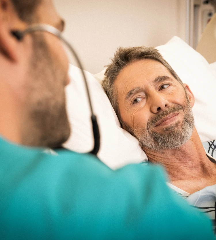 A patient smiles as his doctor listens to his chest with a stethoscope.
