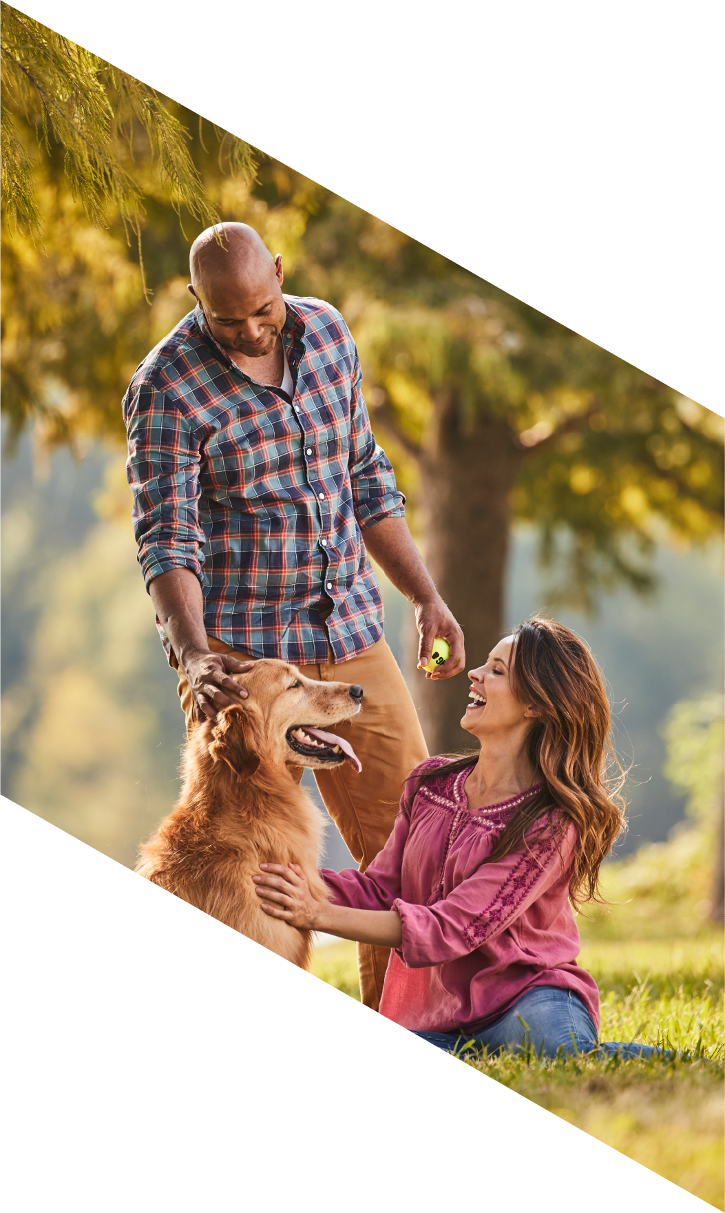 A happy couple enjoys nature and plays ball with their dog.